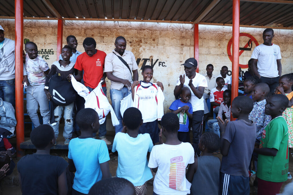 young girl in kenya receive a shirt as a gift in a football pitch